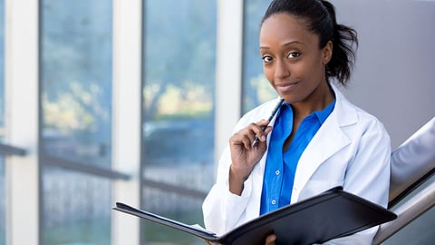 young female pharmacist holding documents while outside a hospital