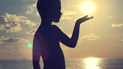 A boy appears to be holding the sun