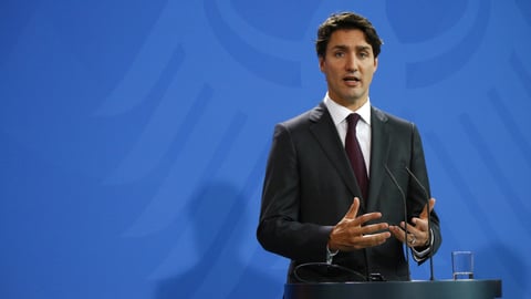 Prime Minister Justin Trudeau speaking in front of a blue background