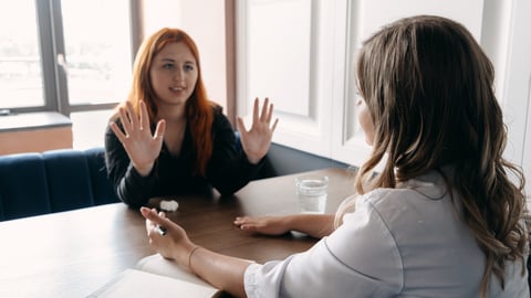 Two women speaking at a desk