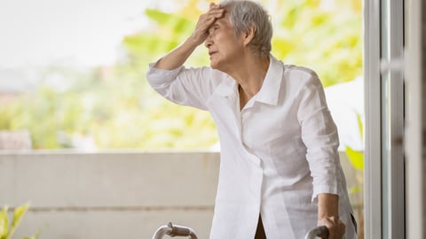 Older woman placing her hand on her head because she's too hot