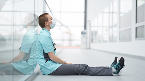 Exhausted doctor sitting by the side of a wall