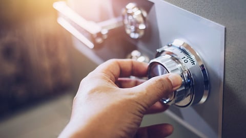 closeup of a hand turning the dial on a safe