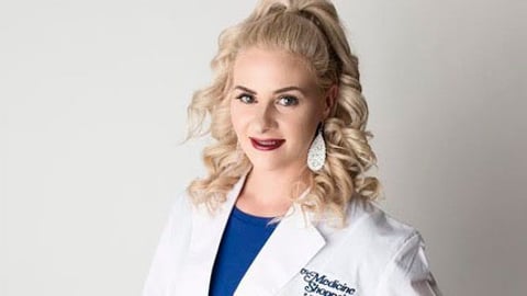 young female pharmacy technician Heather Snook, wearing a white coat and smiling at the camera