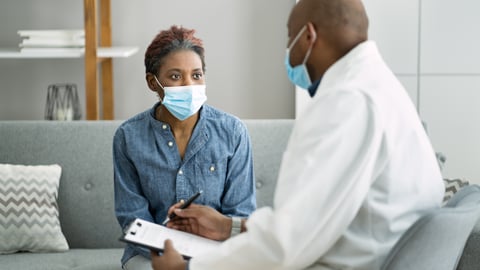 Doctor consulting with patient, with both wearing blue surgical masks