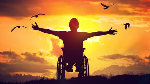 Man in wheelchair with setting sun.