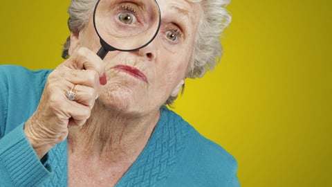 White-haired-woman-holding-magnifying-lens-to-her-eye