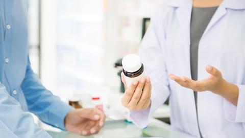 pharmacist consulting with a patient about a bottle of pills