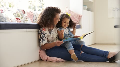 Young woman reading to a child on her lap