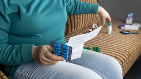 a patient sits on a couch reviewing the information for a new medication