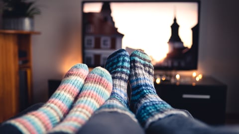 POV image of two people with cozy socks watching TV