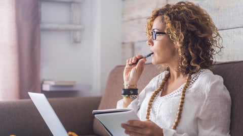 Woman with pen in mouth and journal in hand