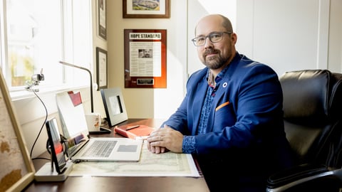 a man sitting at a desk in front of a laptop