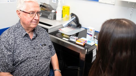 older man sitting with pharmacist in office