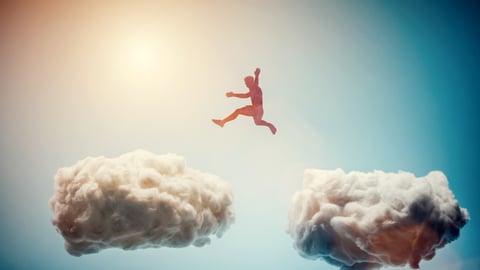 man leaping between clouds in sky