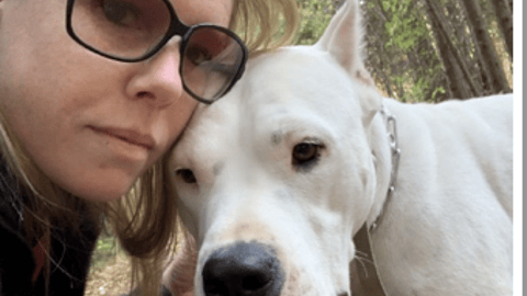 woman in glasses holding white dog