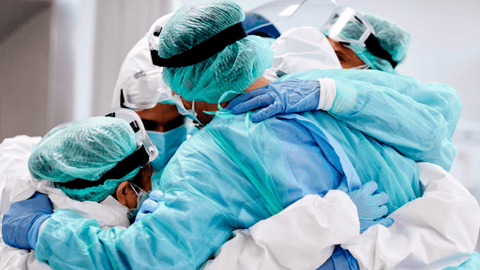 a group of healthcare workers wearing surgical gear, hugging each other