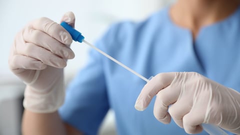 Nurse putting a swab in a test tube