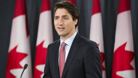 Justin Trudeau speaking in front of a row of Canadian flags