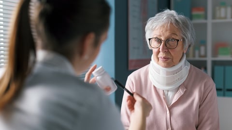 Pharmacist discussing medication with an older woman wearing a neck brace