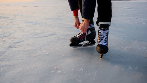 person tying up hockey skates on ice