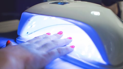 Hand with nail polish under lighted nail dryer