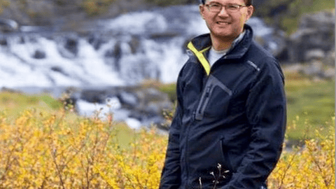 Asian man in field with camera