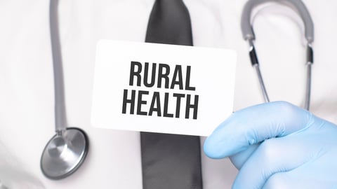 Doctor holding a small sign that says 'Rural Health'