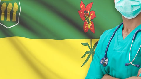 Doctor in front of the Sask. flag