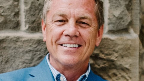 Middle-aged white man smiling in a blue suit