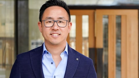 Asian-man-glasses-smiling-in-front-of-building