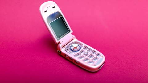 Pink flip phone on a pink background