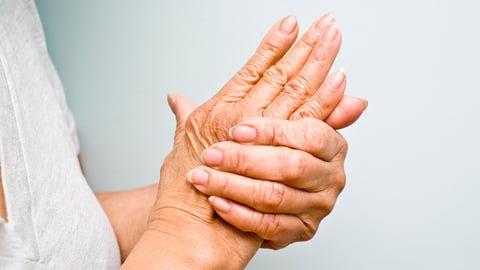 Close-up of older white woman rubbing her hands together in pain