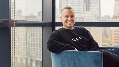 Jaris Swidrovich sitting and smiling in front of a large window