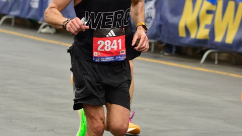 Man running in a black outfit with a racing bib