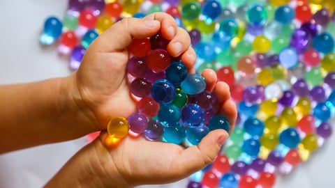 Young child's hands cupping a plentiful handful of coloured beads