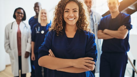 Team of healthcare workers with young woman smiling in the foreground