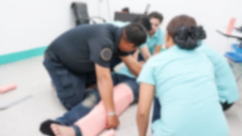 blurry image of healthcare workers treating patient on ground with bad leg