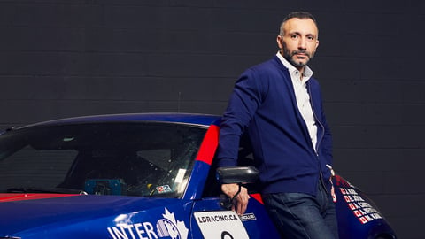 Man in a blue suit sitting on a blue car