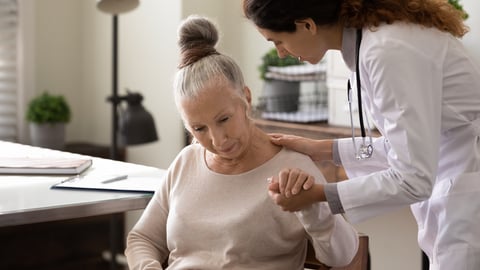 Young woman doctor comforting an older patient