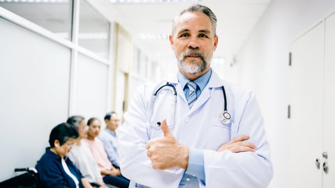 white-male-doctor-with-beard-standing-arms-crossed-thumbs-up