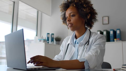 female physician typing on a laptop comuter