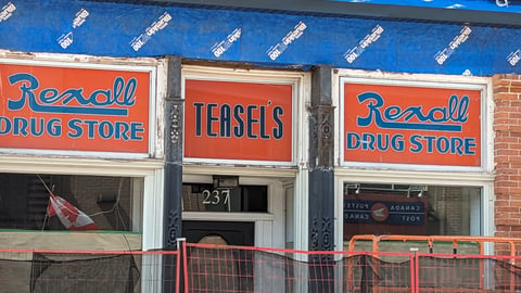 An old building with orange and blue sign reading Teasel’s Drug Store