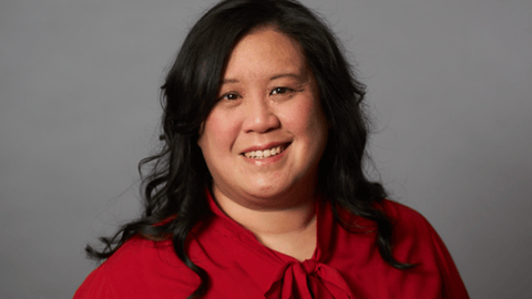 A smiling woman with dark hair wearing a red shirt