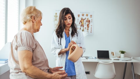 White woman doctors discussing a knee brace with an older patient