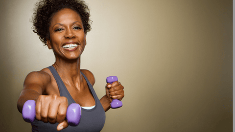 black woman smiling while pushing purple weights