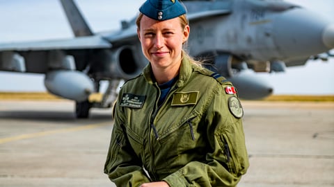 Dr. Thorgrimson crouched in front of helicopter, in uniform