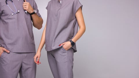 Torsos of two young fashionable doctors wearing purple scrubs