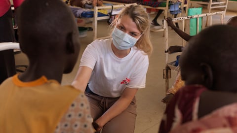 Dr. Paquet facing the camera, treating two young Black patients, seen from behind