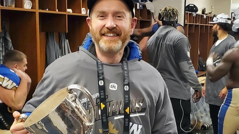 Dr. Morrow holding Grey Cup, cropped to see just top of Cup